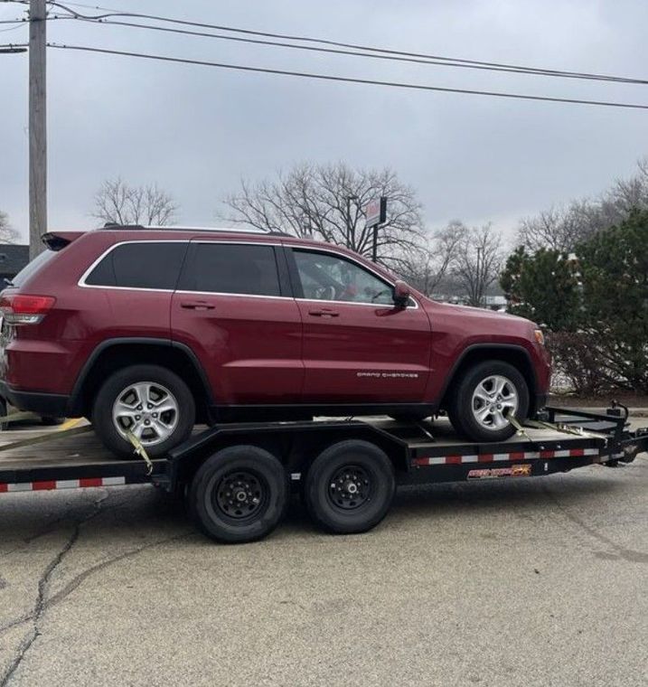 A black tow truck towing a red car on a street.