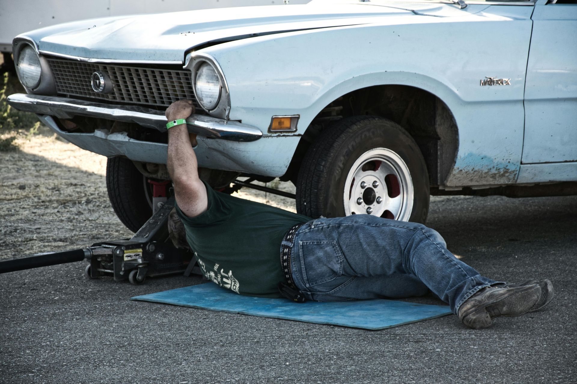 A tow truck operator secures a blue car onto the flatbed.