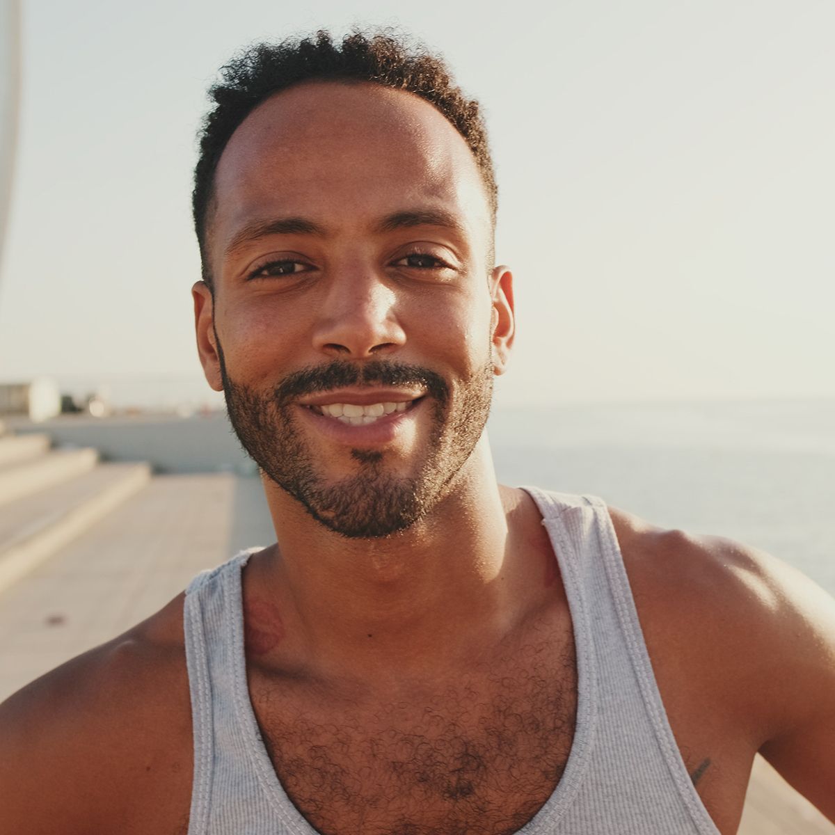 A man with a beard is wearing a tank top and smiling