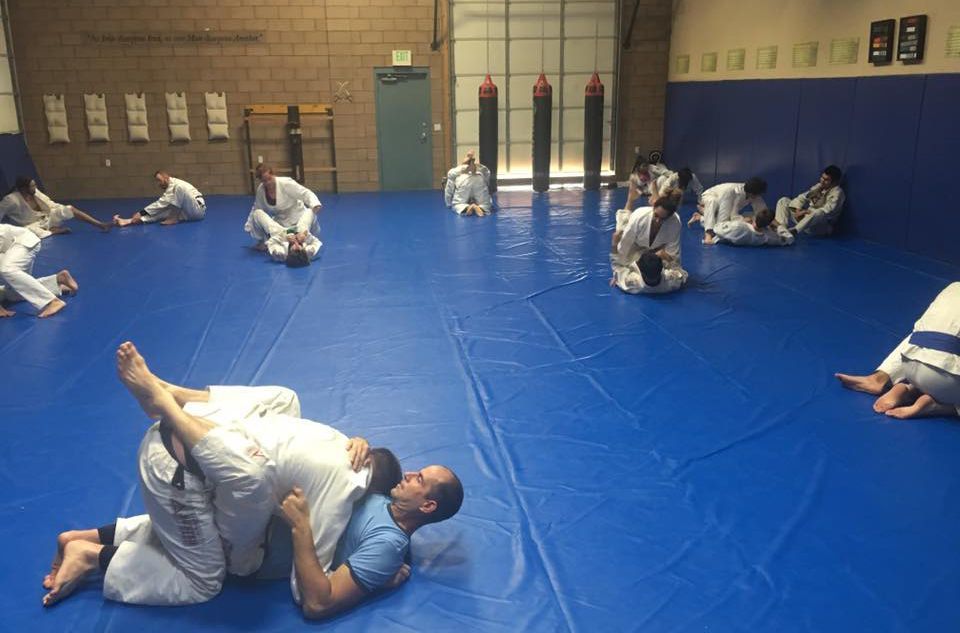 A group of people are practicing martial arts on a blue mat.