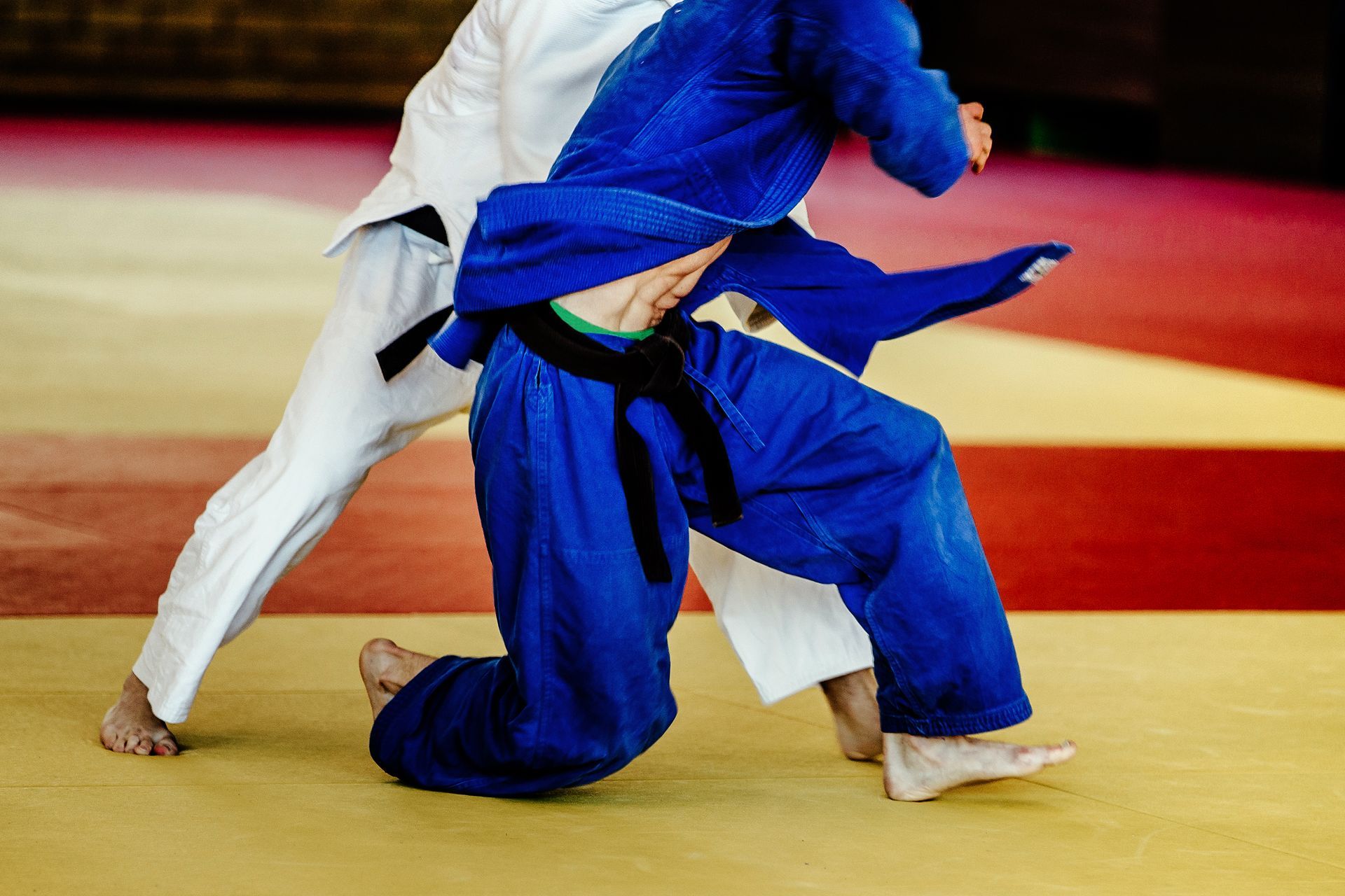 Two men are fighting in a judo match on a mat.