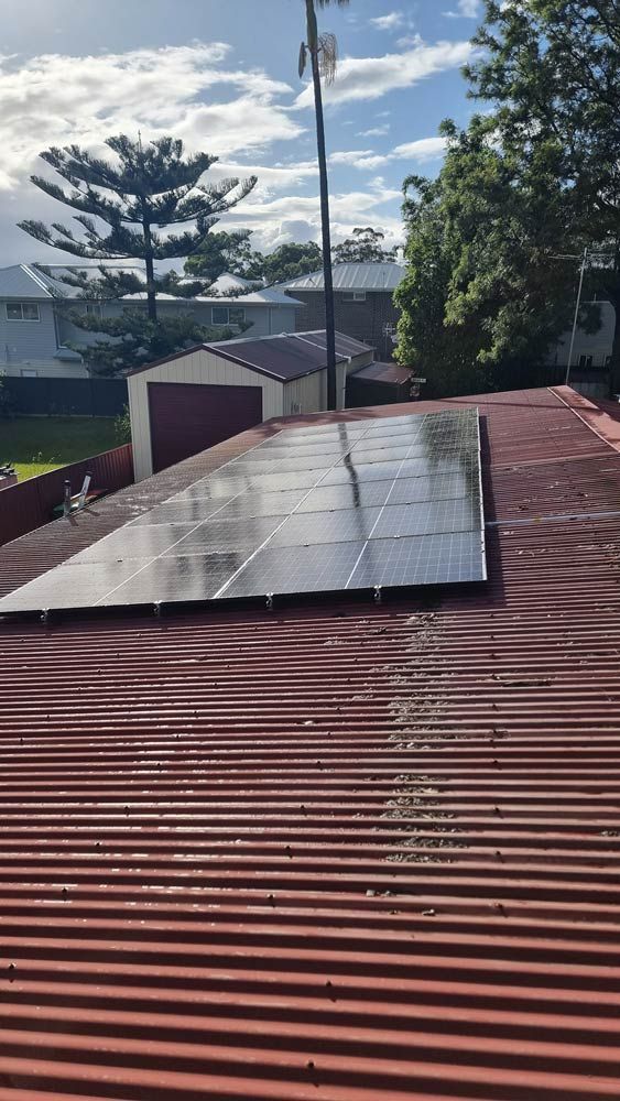 A Brick House With Solar Panels on the Roof — JNQ Solar & Electrical in Campbelltown, NSW