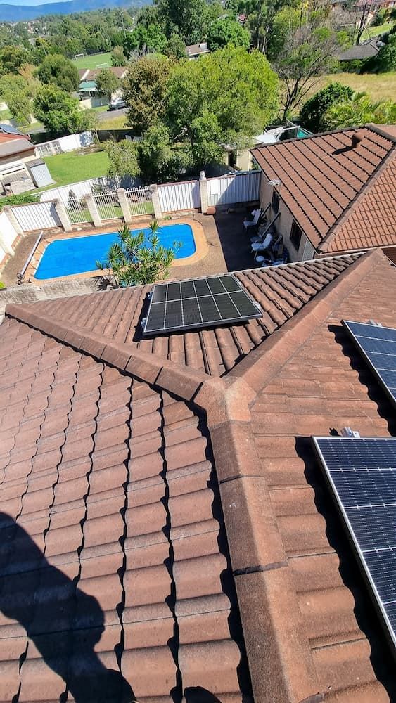 A Roof With Solar Panels on It and a Pool in the Background — JNQ Solar & Electrical in Campbelltown, NSW