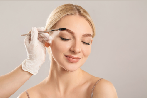 Woman getting her eyebrow brushed by someone wearing a glove. — Aqua Marine Skin and Beauty in Tuncurry, NSW