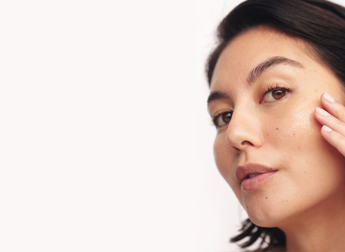 Woman touching her face, looking at the camera. She has freckles and is against a white background — Aqua Marine Skin and Beauty in Tuncurry, NSW