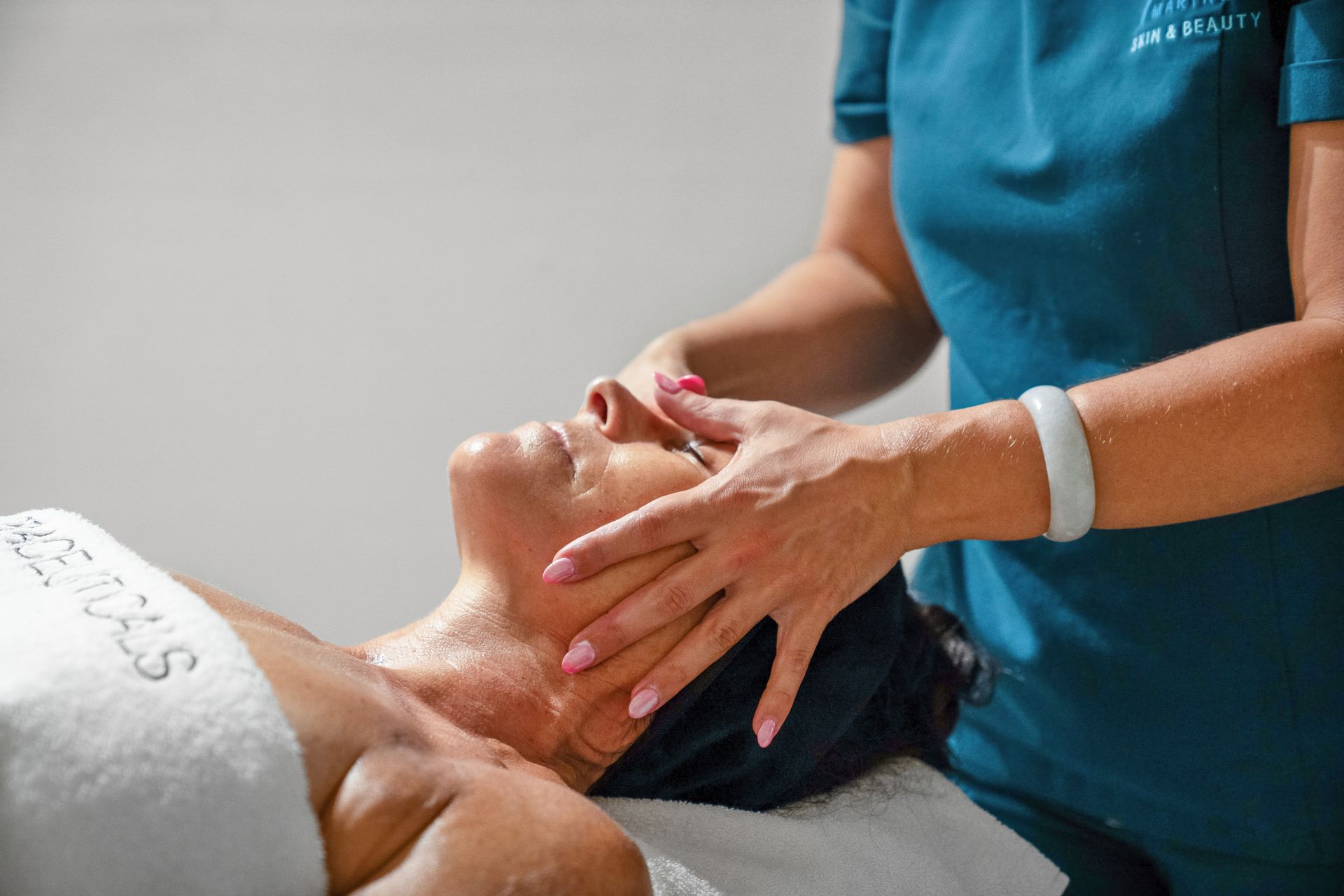 Woman Receiving Facial Treatment; Therapist's Hands on Her Face — Aqua Marine Skin and Beauty in Forster, NSW