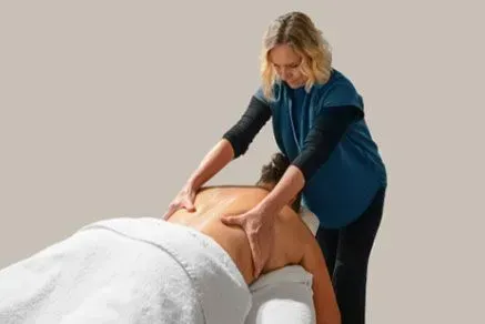 Massage Therapist Giving a Back Massage on a Patient Lying on a Table — Aqua Marine Skin and Beauty in Tuncurry, NSW