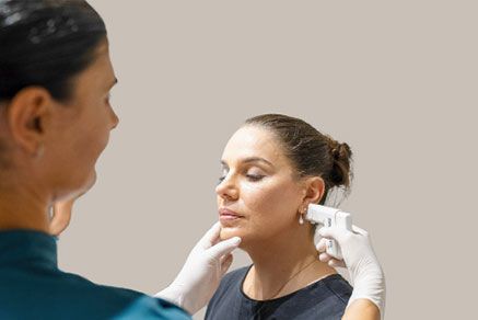 Woman receiving cosmetic procedure on her face. Doctor in gloves holds device near her cheek. — Aqua Marine Skin and Beauty in Tuncurry, NSW