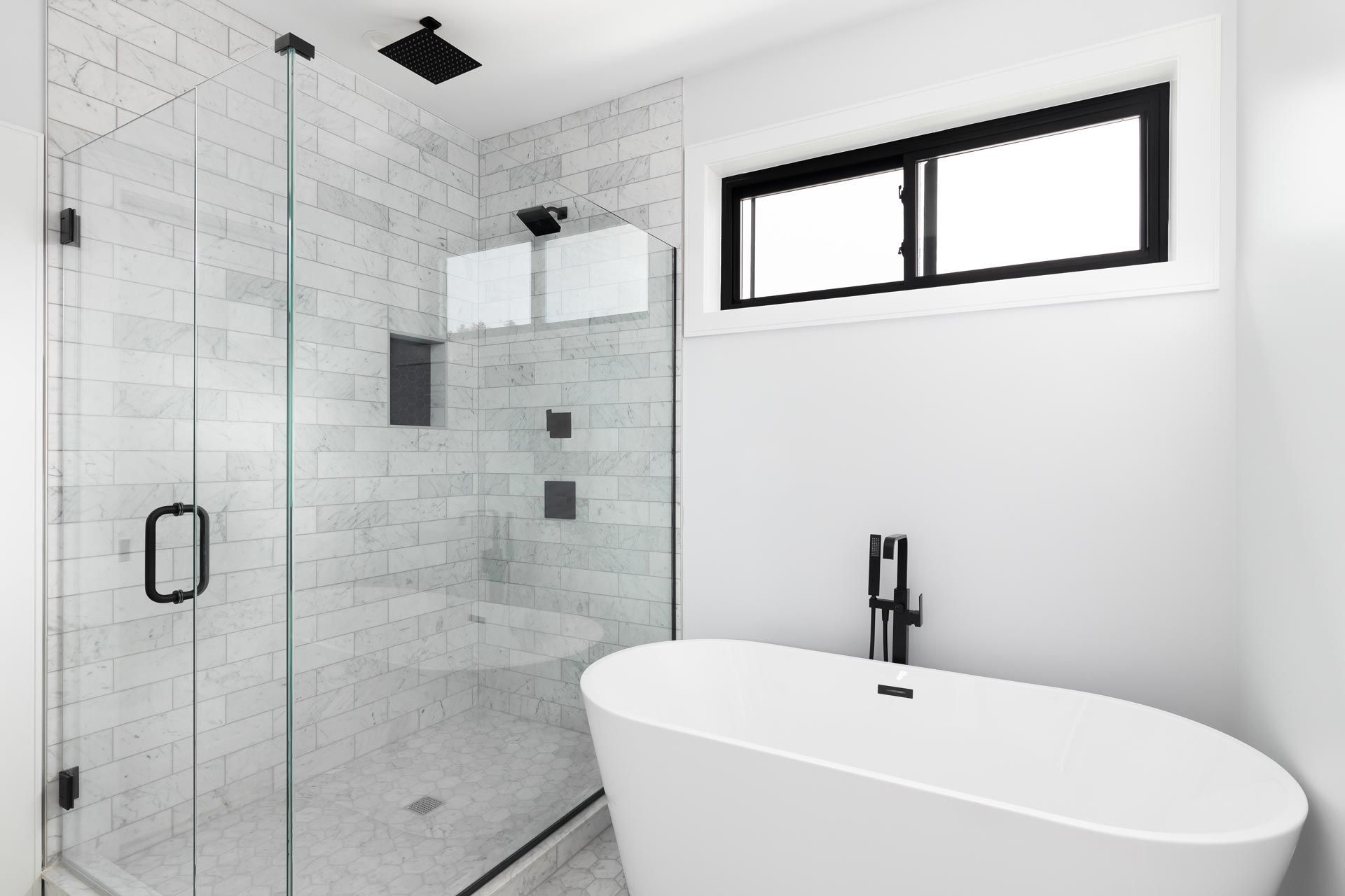 Modern bathroom with frameless glass from a shower door shop, featuring white tile and tub.
