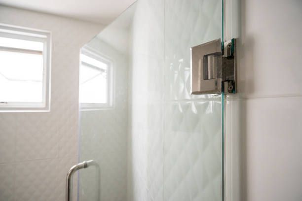A bathroom with a glass shower door and a window.