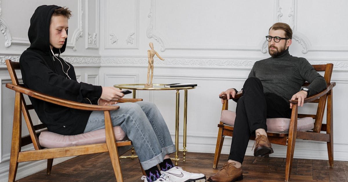 Two men are sitting in chairs talking to each other.