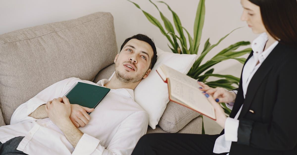 A man is laying on a couch talking to a woman for therapy