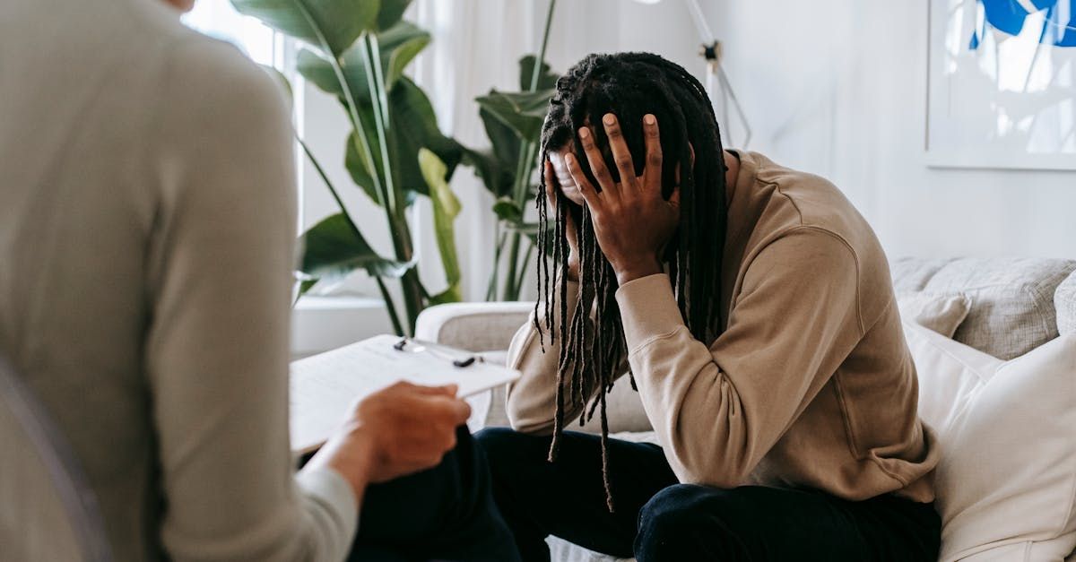 man holding his head in his hands in a therapists office