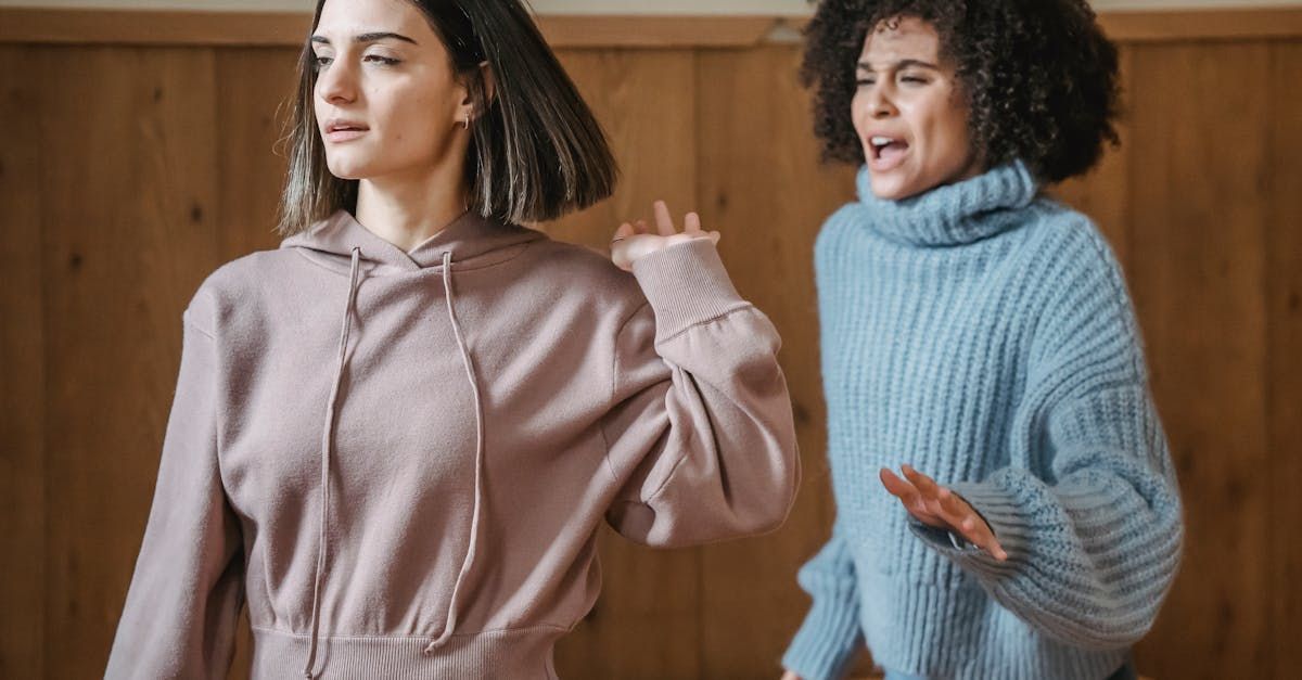 Two women are standing next to each other in front of a wooden wall.