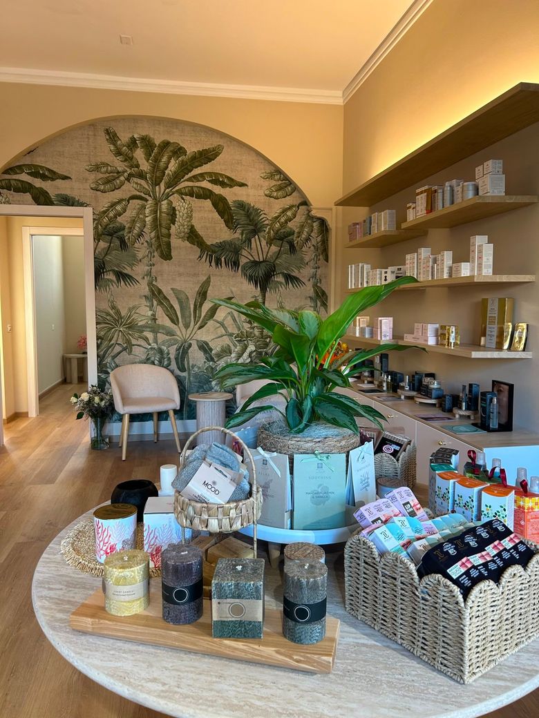 In una stanza illuminata da una luce calda, un'esposizione in stile boutique di candele, vasetti e articoli da regalo è allestita su un tavolo rotondo.
