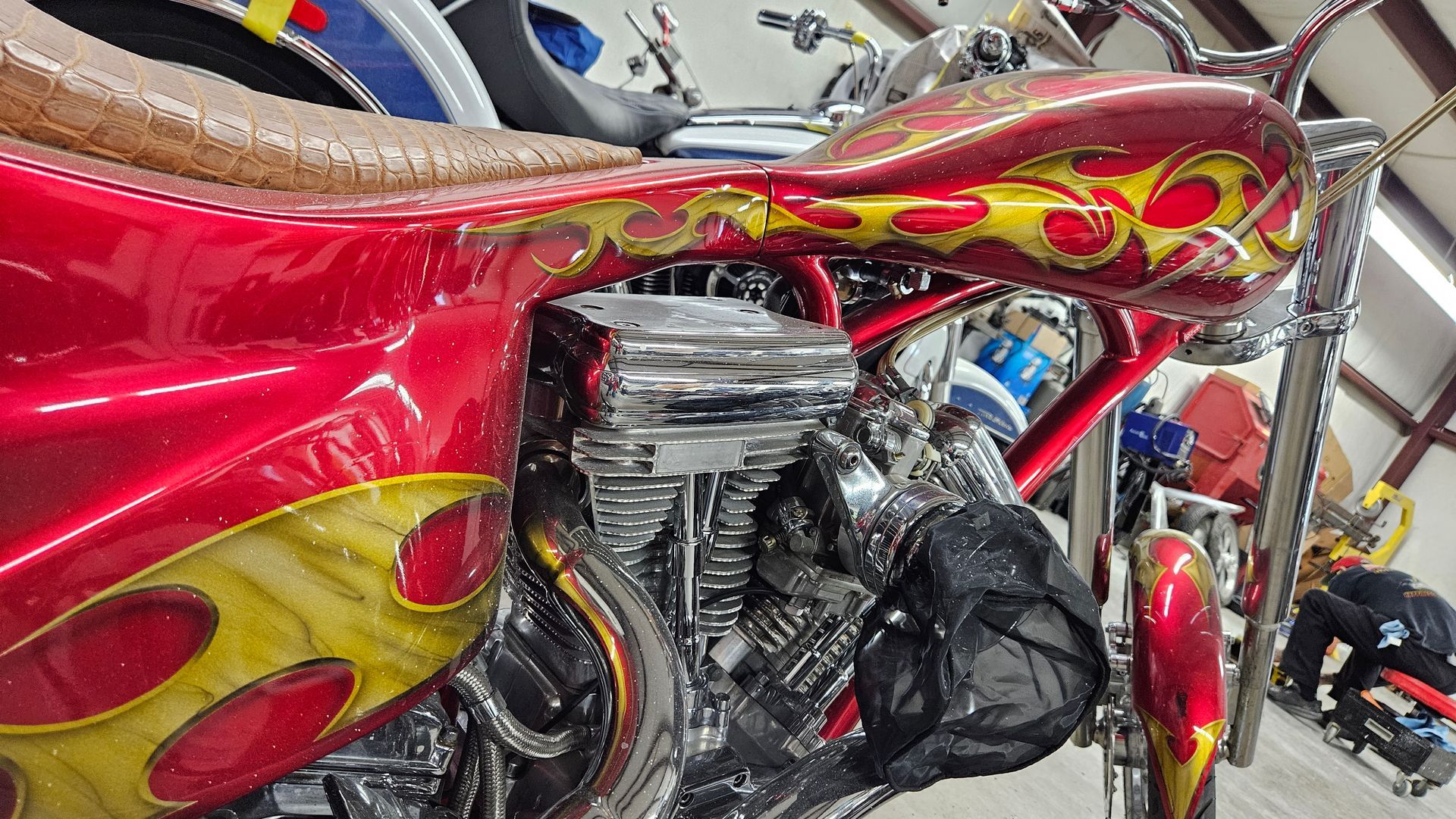 A red motorcycle with flames painted on it is parked in a garage.