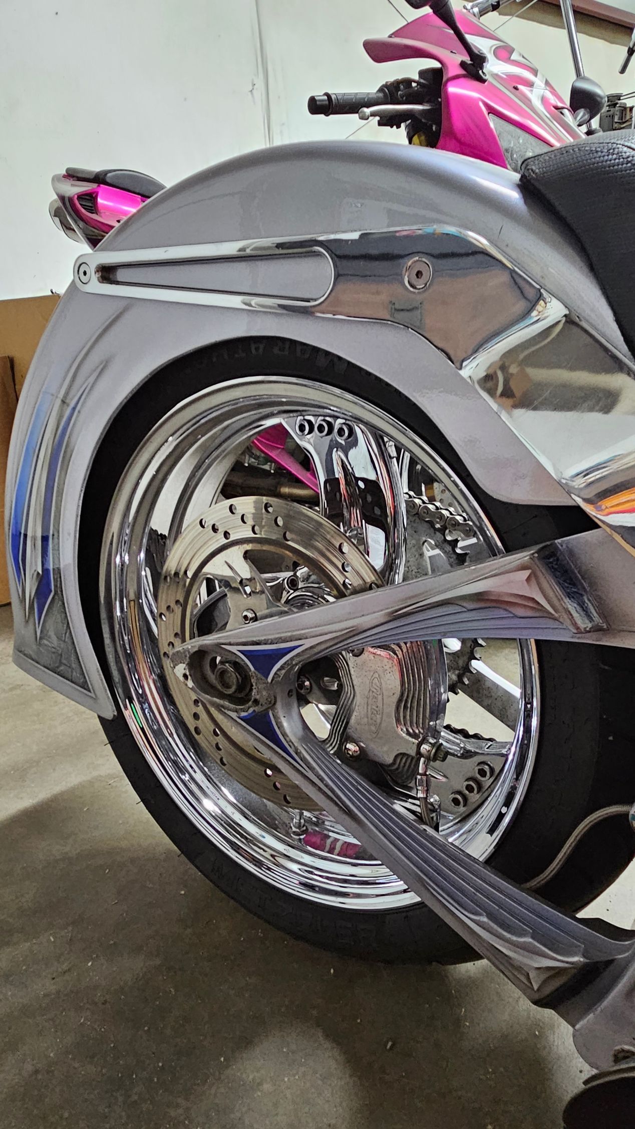 A close up of the rear wheel of a motorcycle in a garage.