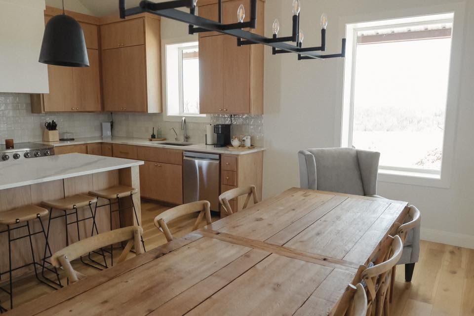 A kitchen with a wooden table and chairs and a large window.
