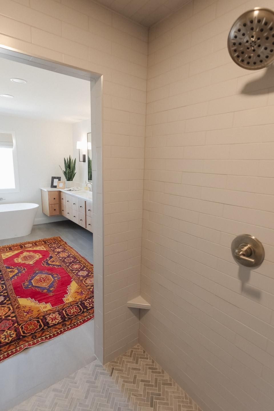 A bathroom with a walk in shower and a rug on the floor.