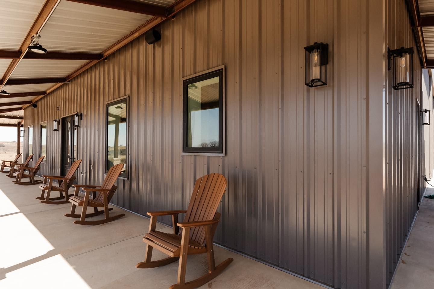 A row of rocking chairs are sitting on a porch of a building.