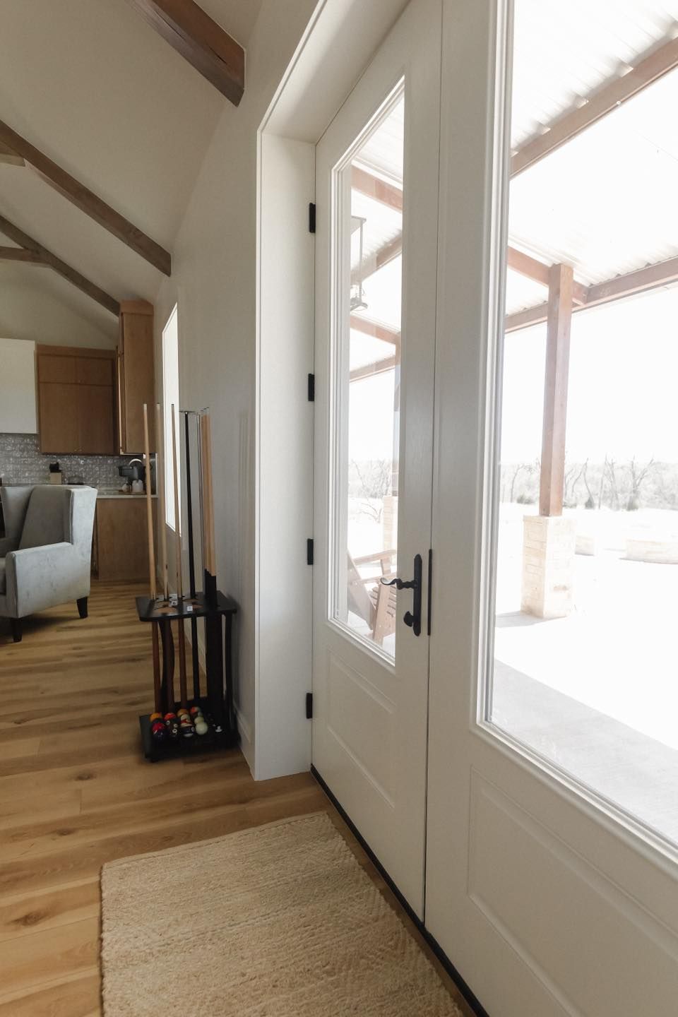 A white door is open to a living room with a rug on the floor.