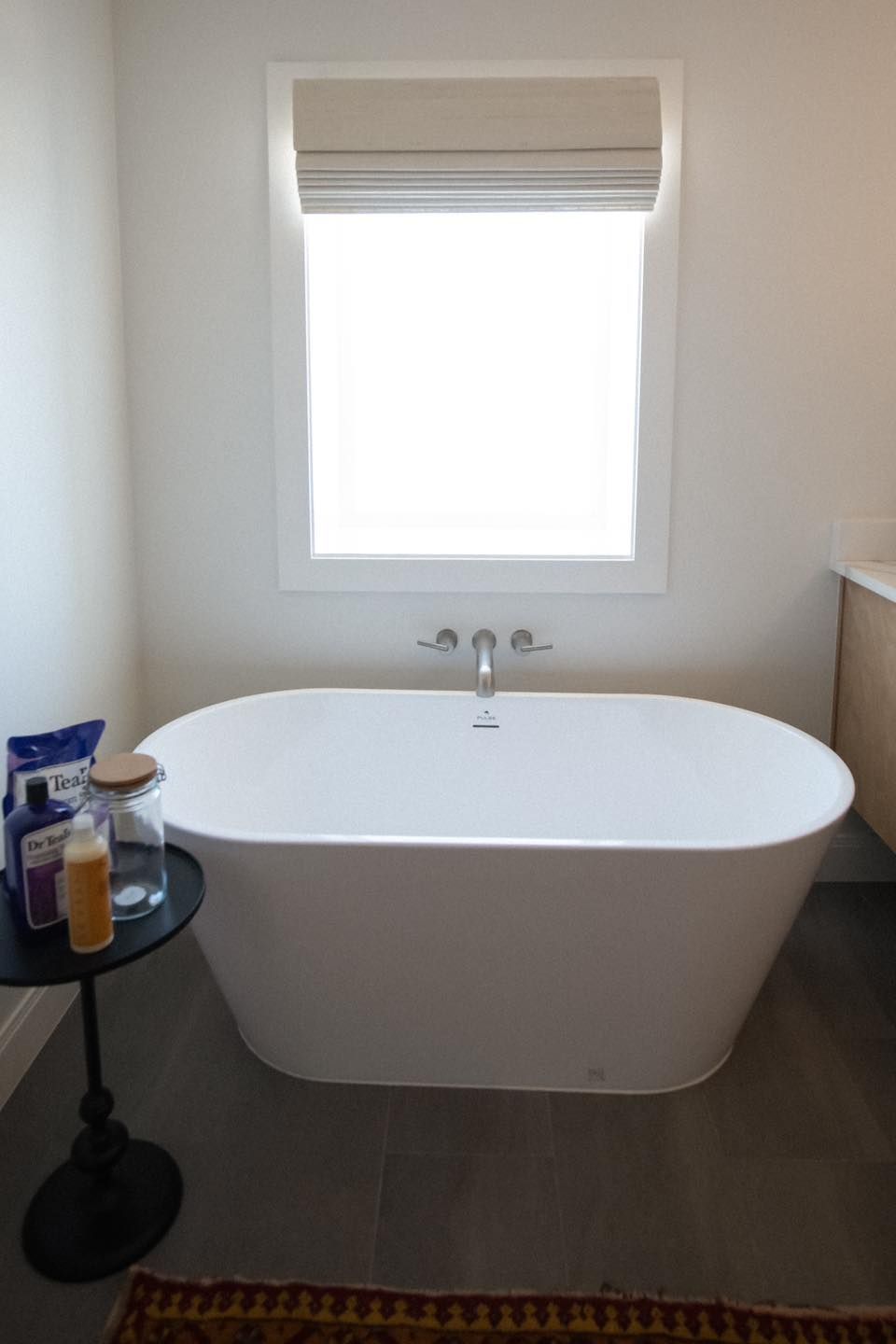 A bathtub in a bathroom next to a window.