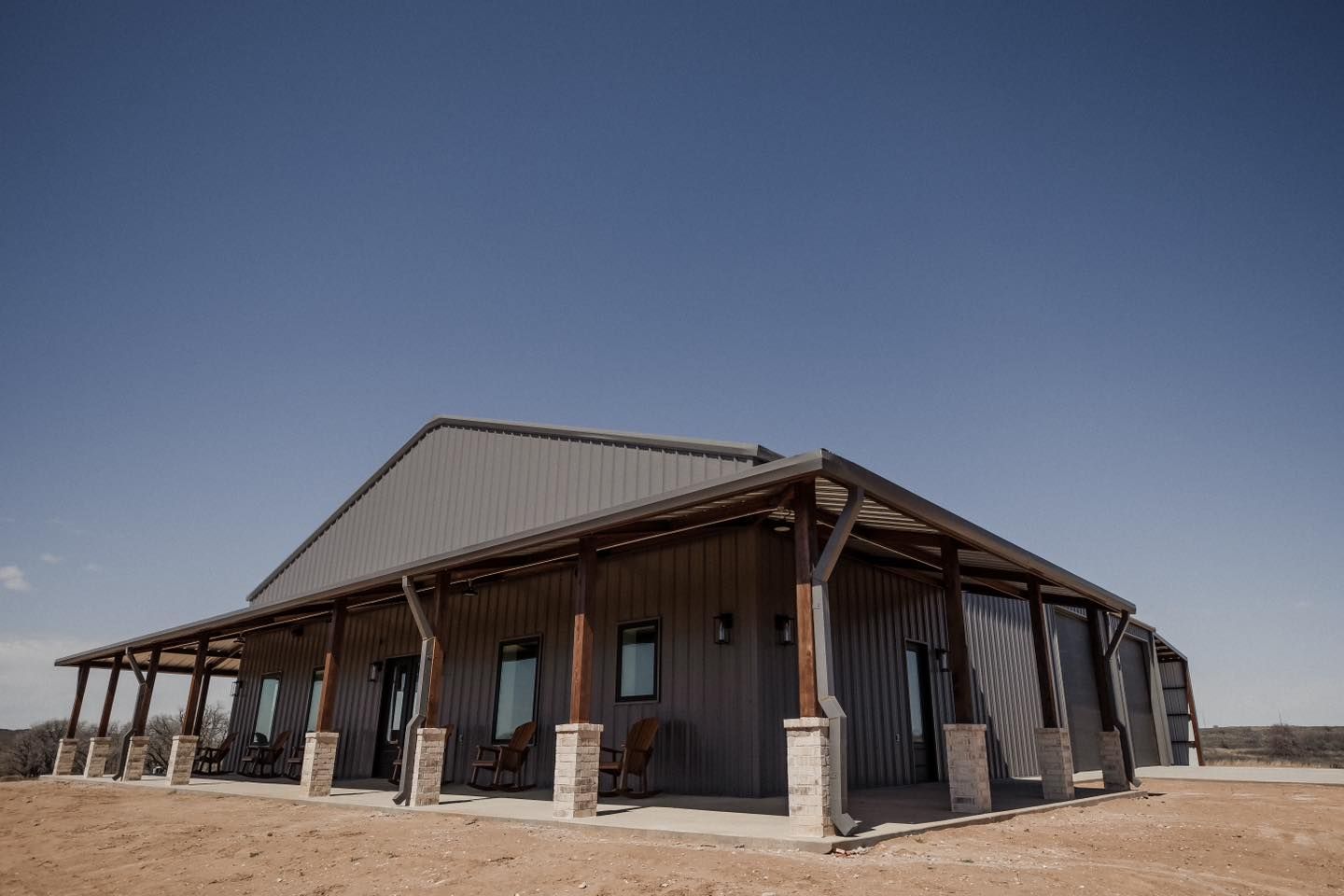 A large metal building with a porch and chairs on it.