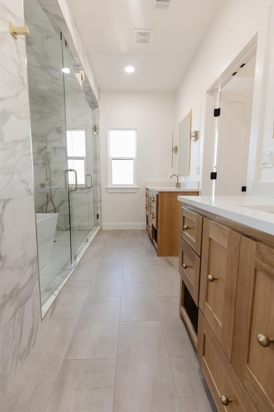 A bathroom with two sinks and a walk in shower.