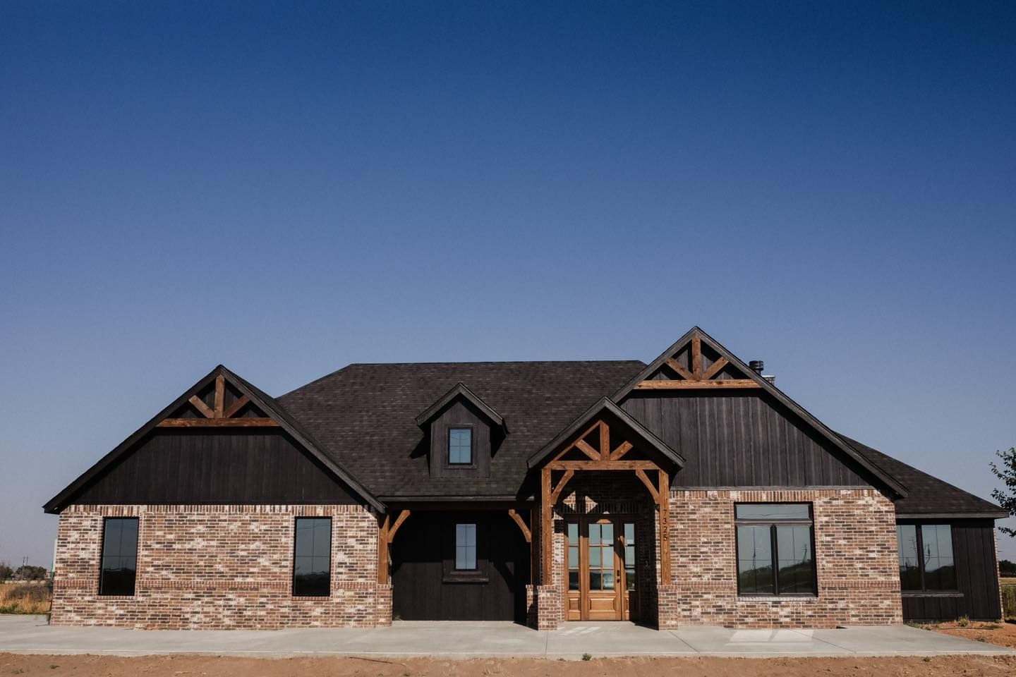 A large brick house with a black roof and wooden trim.