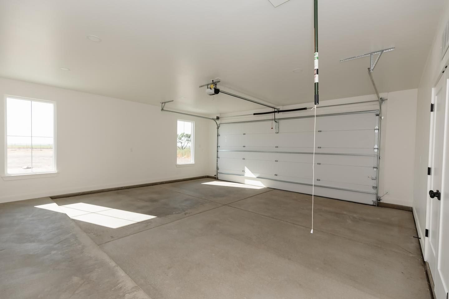 An empty garage with a garage door open and a ceiling fan.