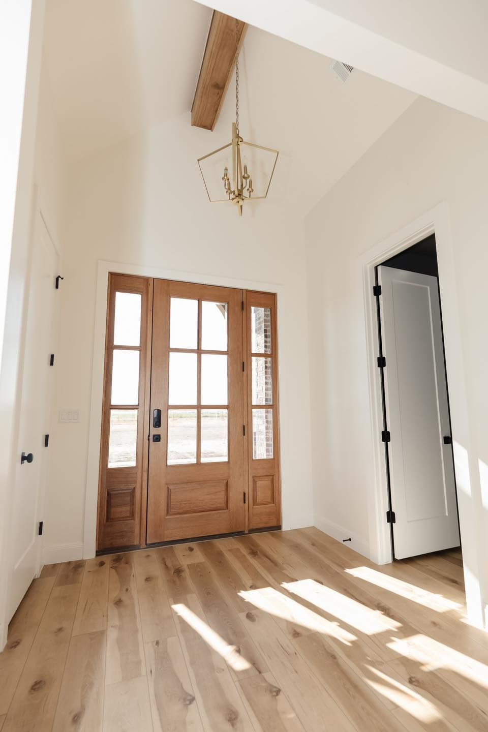 A hallway with a wooden door and a chandelier hanging from the ceiling