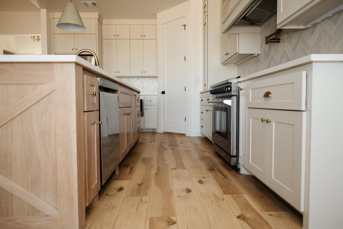 A kitchen with hardwood floors , white cabinets and stainless steel appliances.
