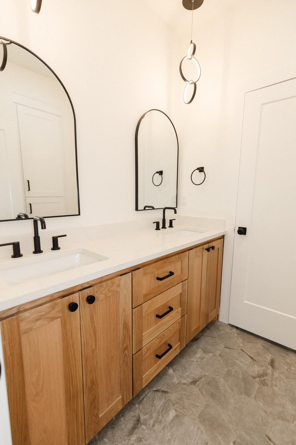 A bathroom with two sinks , a mirror and wooden cabinets.