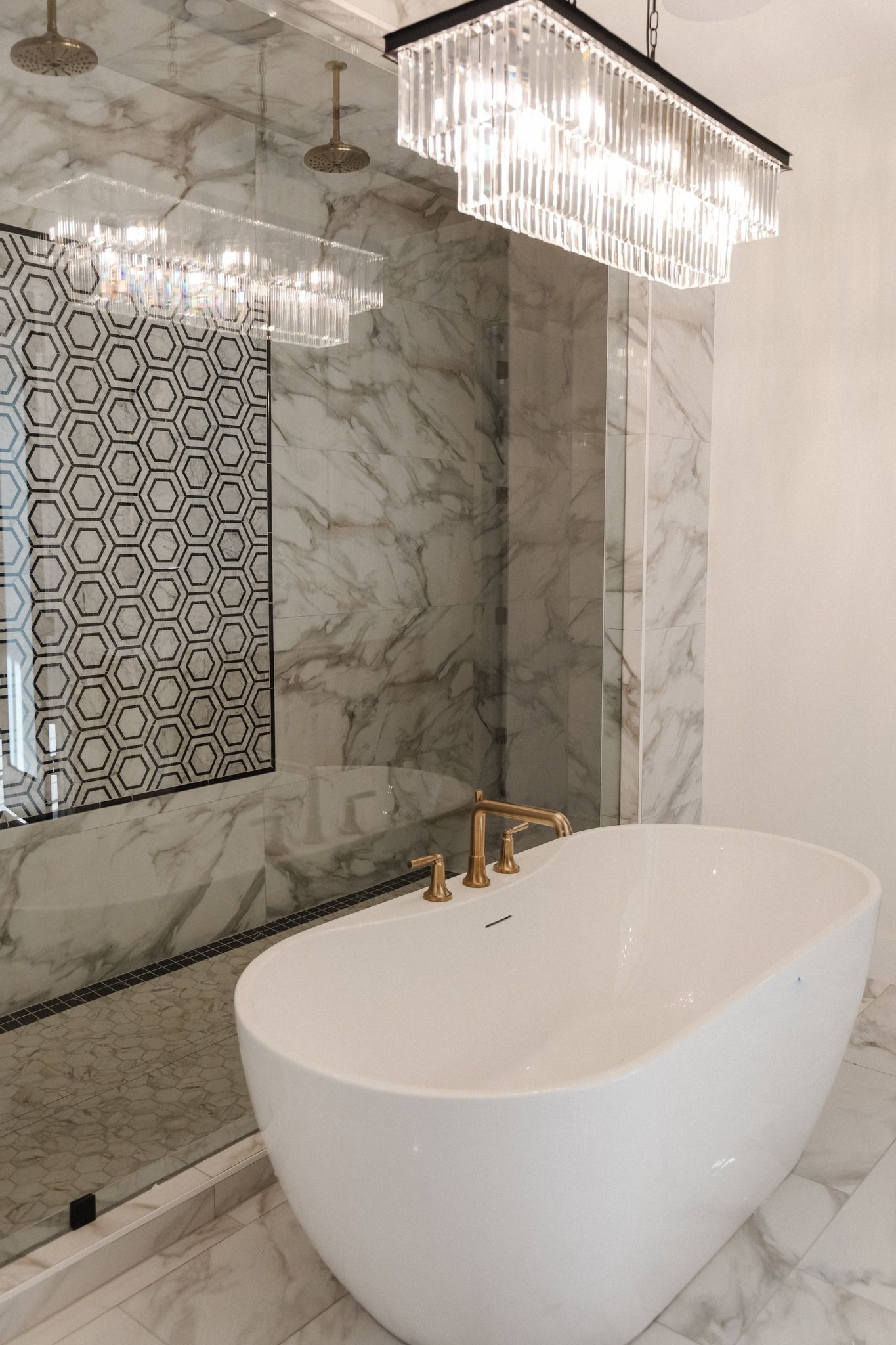 A bathroom with a bathtub , shower , and chandelier.