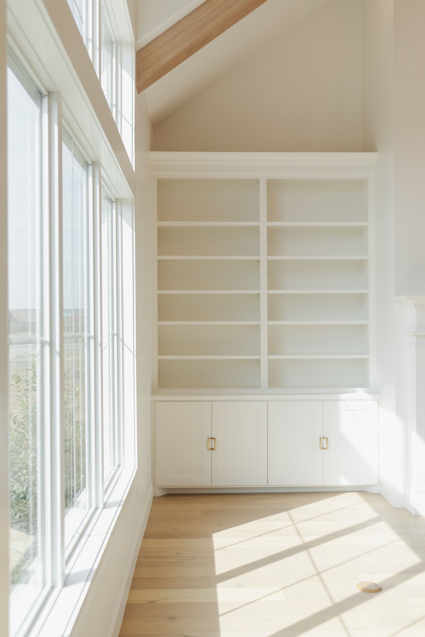 A room with a lot of windows and shelves in it.