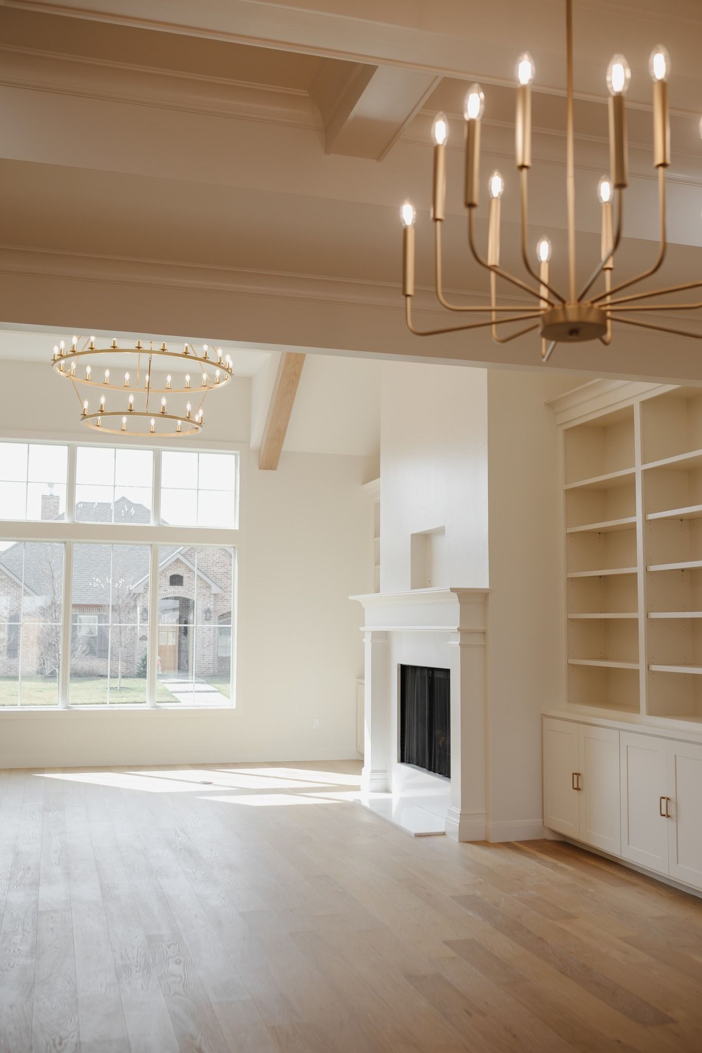 An empty living room with a fireplace and a chandelier.