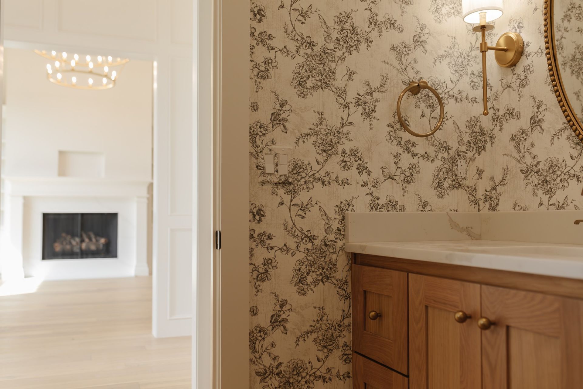A bathroom with a sink , mirror , and floral wallpaper.