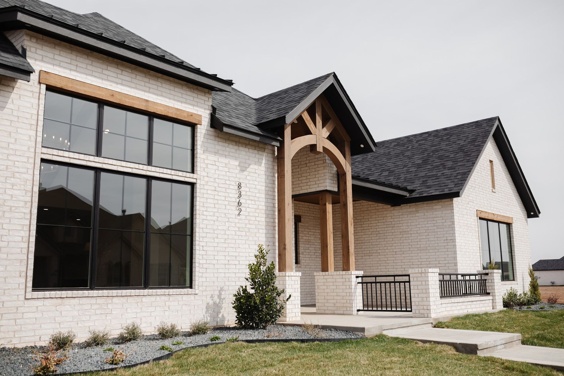A white brick house with black windows and a black roof.