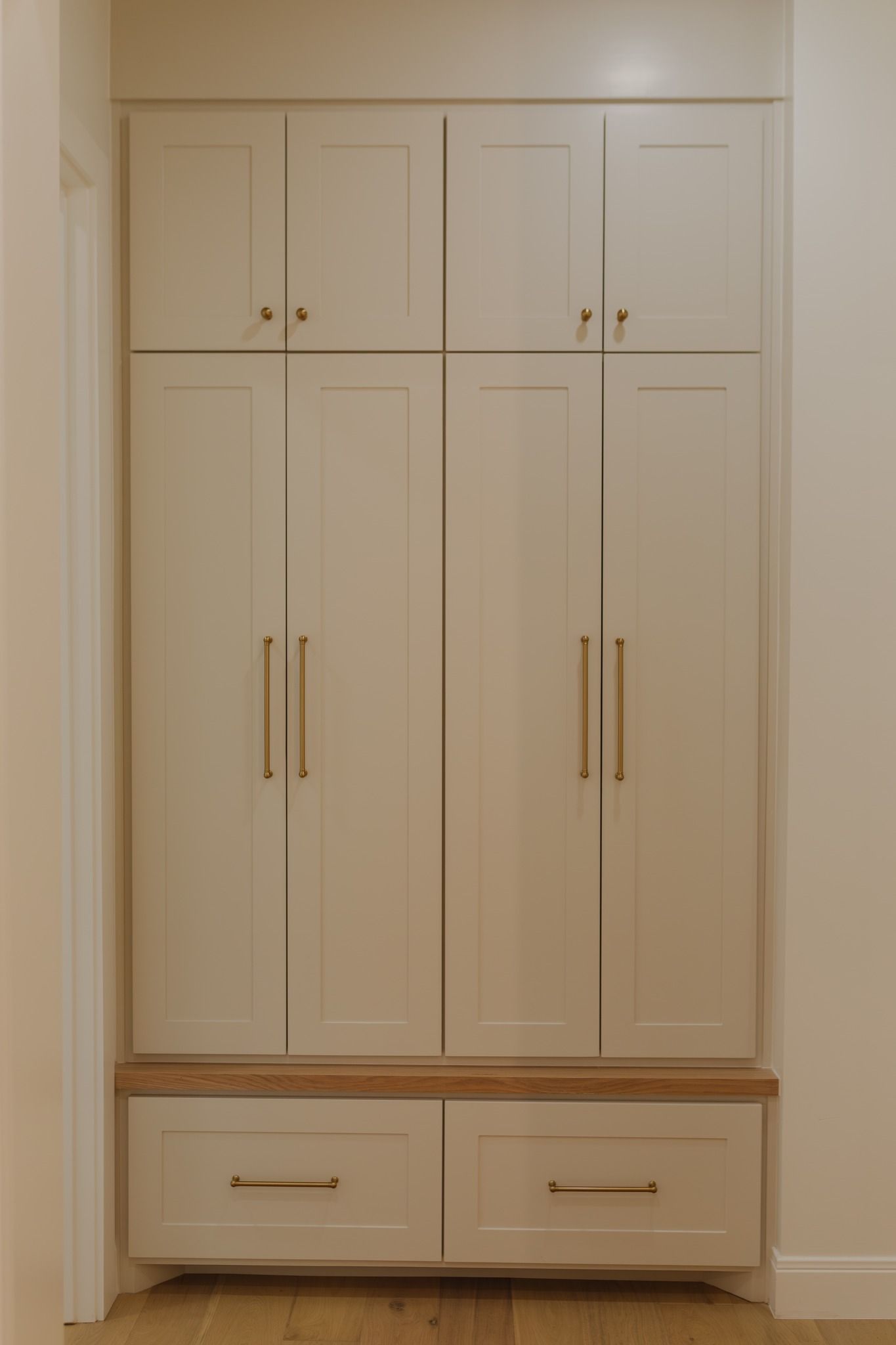 A white cabinet with drawers and doors in a hallway.