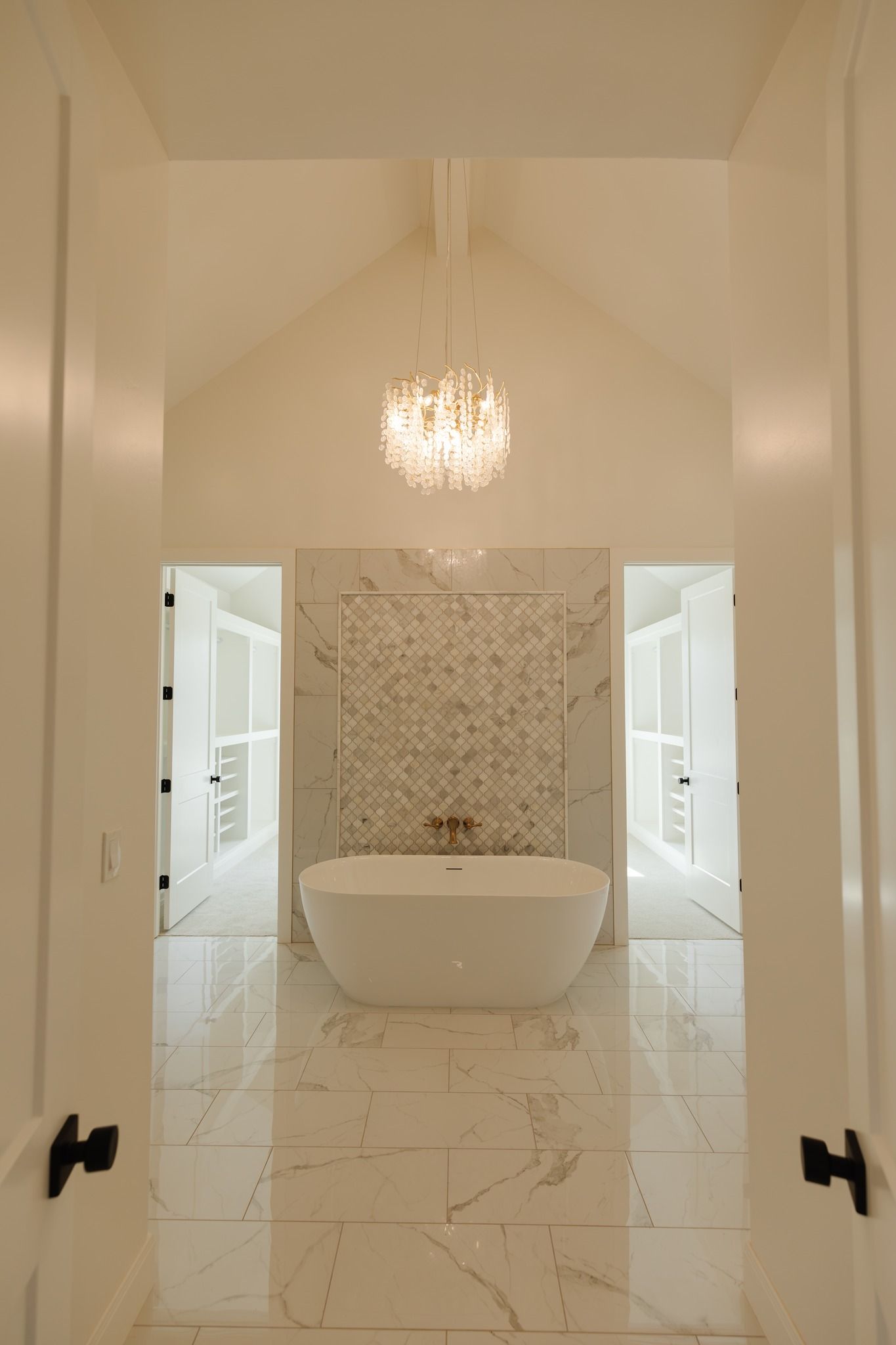 A bathroom with a bathtub and a chandelier hanging from the ceiling.