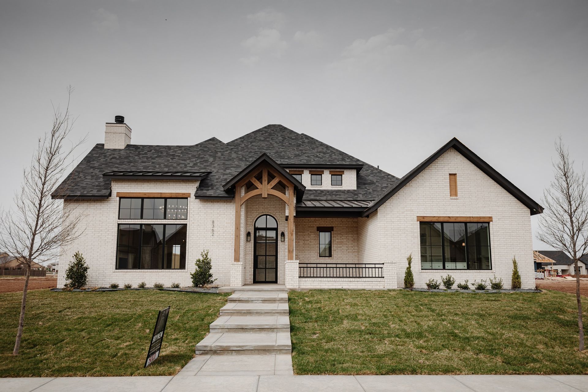 A large white house with a black roof is sitting on top of a lush green lawn.