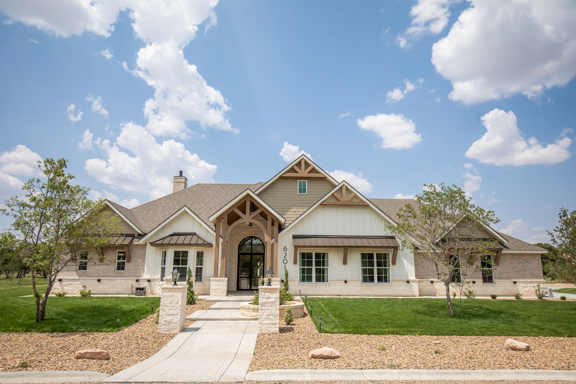 A large white house with a gray roof and a walkway leading to it.