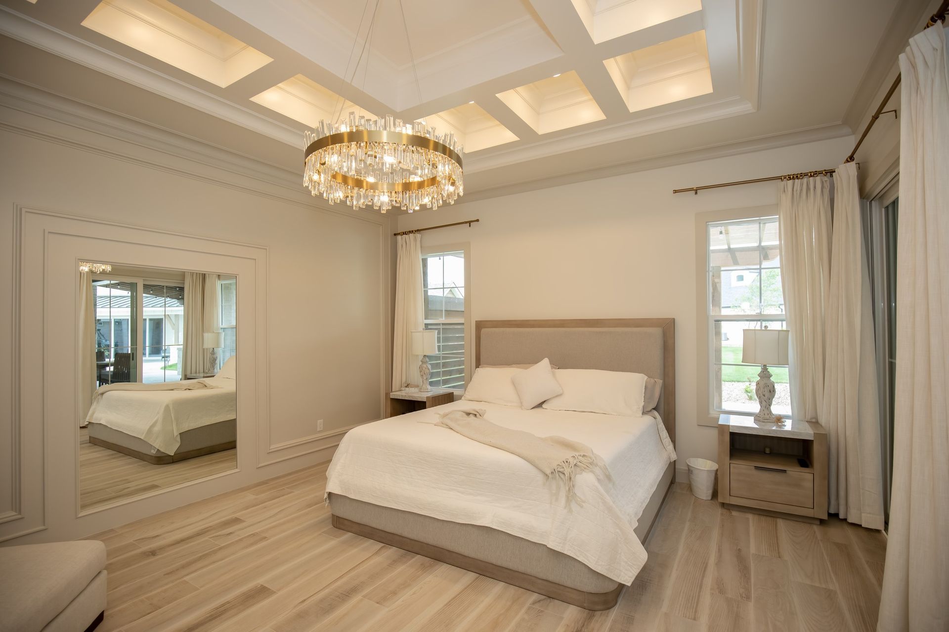 A bedroom with a large bed and a chandelier hanging from the ceiling.