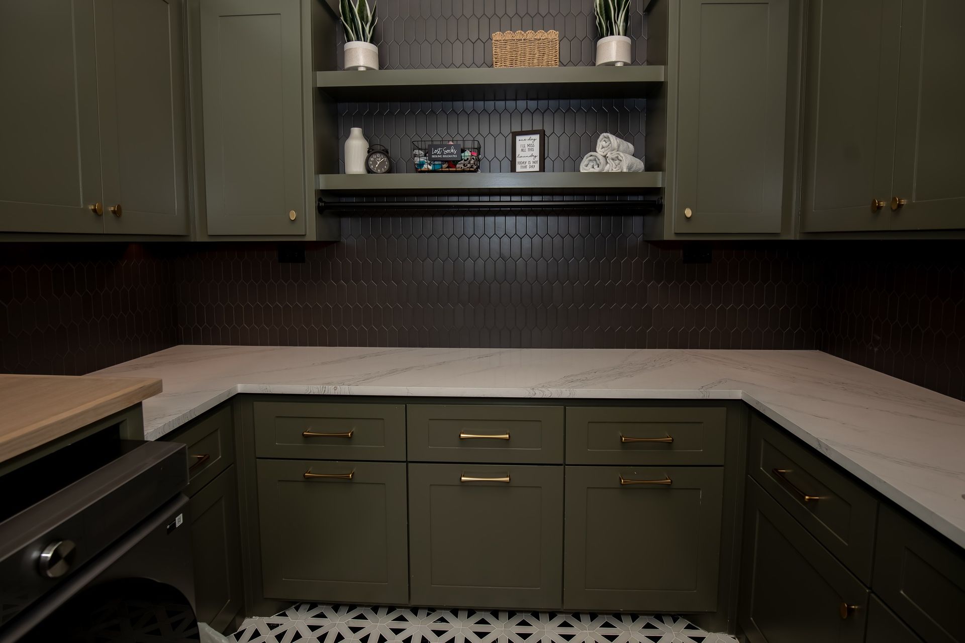 A kitchen with green cabinets and white counter tops.