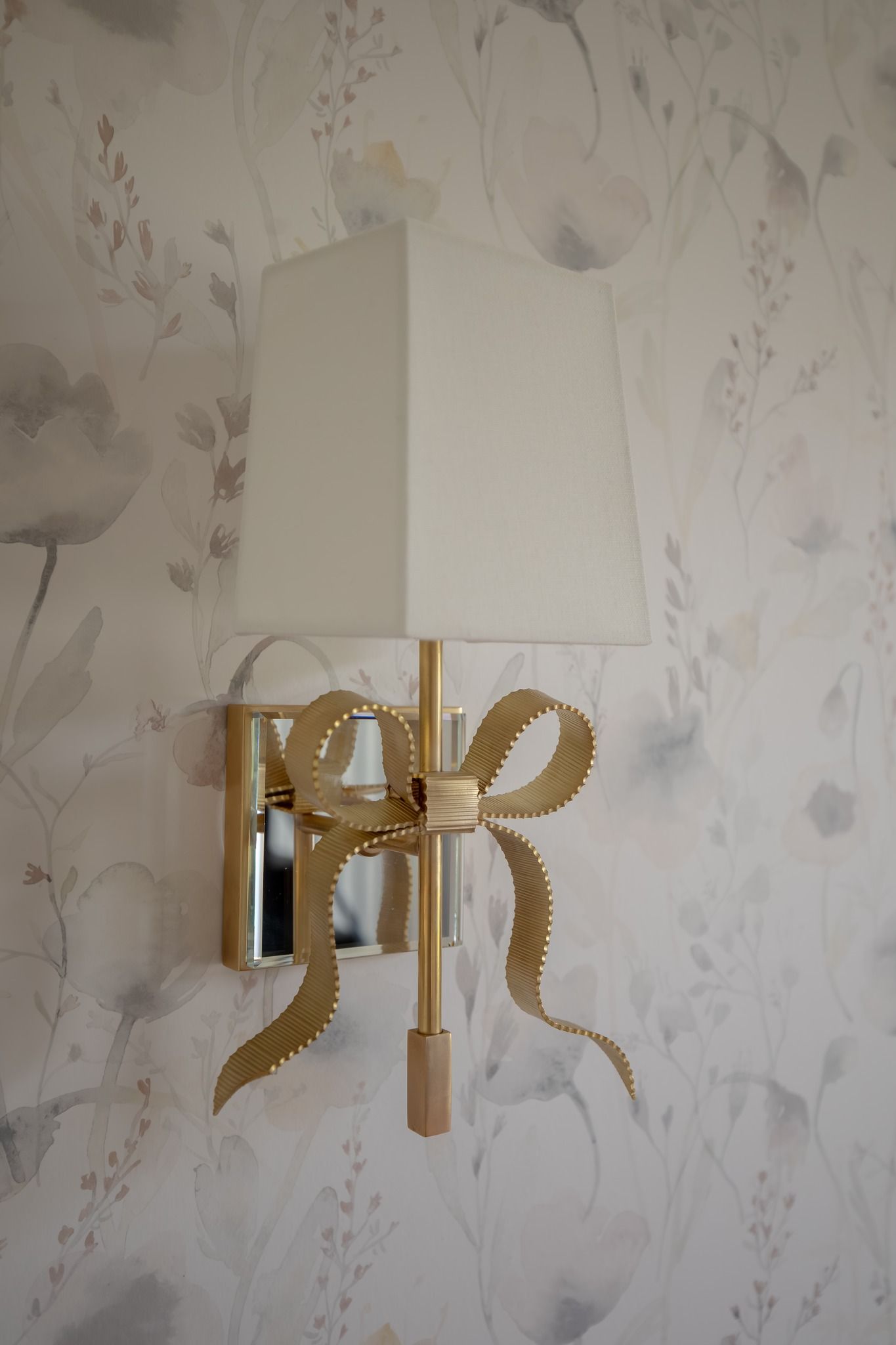 A lamp with a bow on it is hanging on a wall.