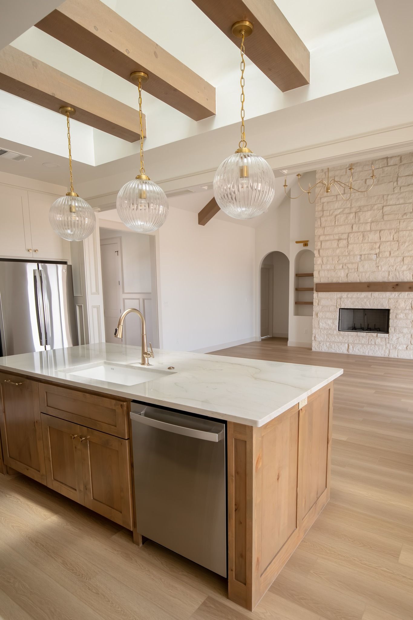 A kitchen with a large island , stainless steel appliances , wooden cabinets and a fireplace.