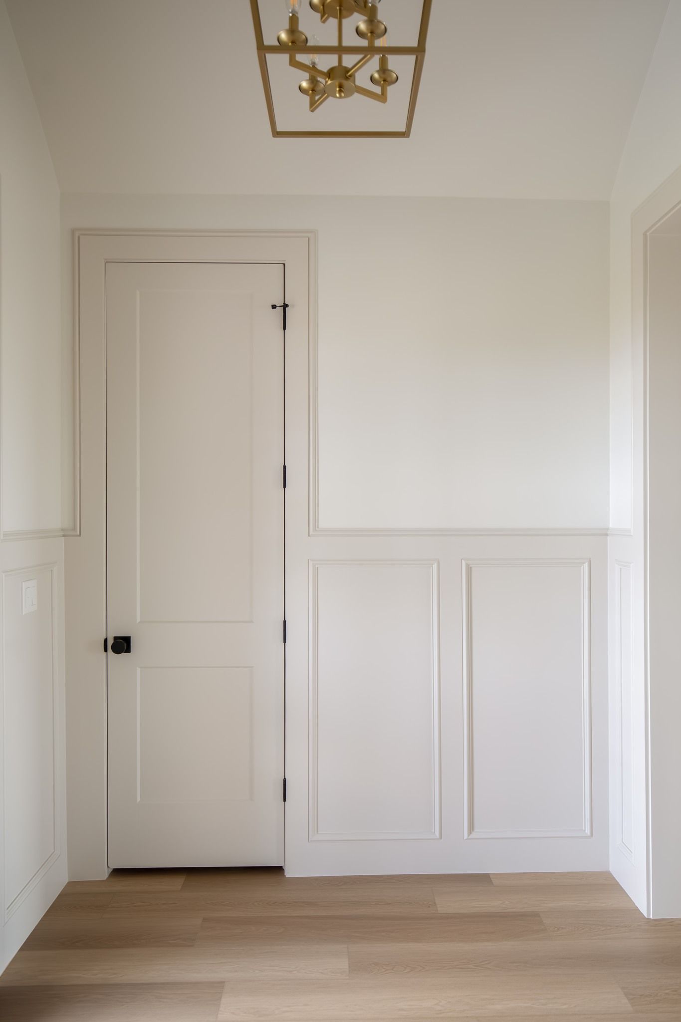 A hallway with white walls and wooden floors and a lantern hanging from the ceiling.