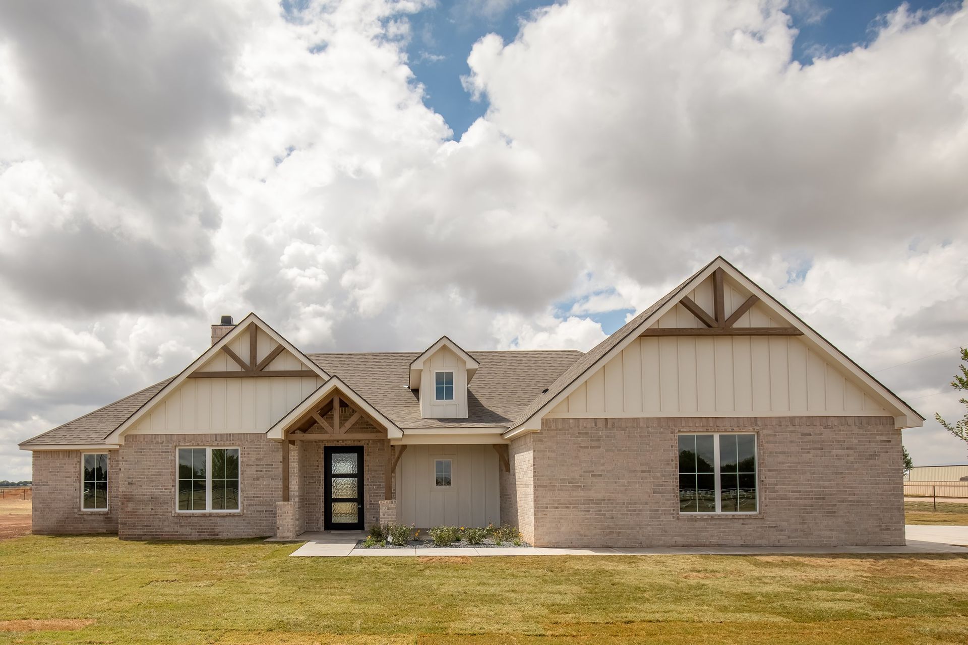 A large brick house with a lot of windows is sitting on top of a lush green field.