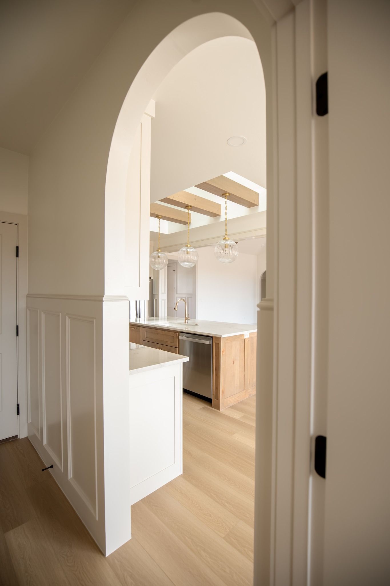A view of a kitchen through an archway in a house.