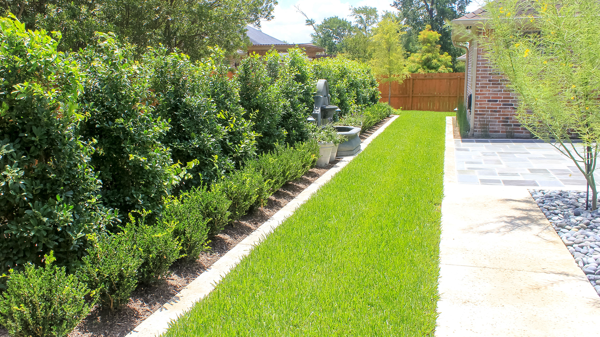 A lush green lawn with a stone walkway leading to a house.